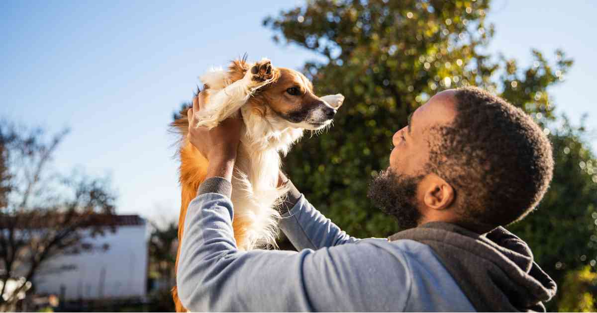 Man lifting his dog and gazing at it affectionately.